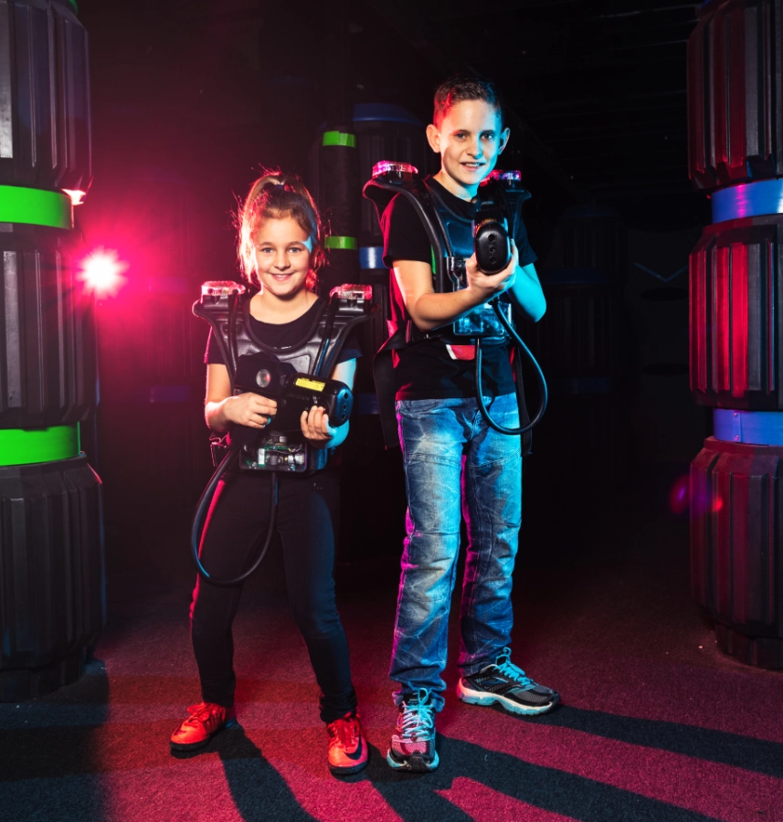 Ein Mädchen und ein Bub mit Phaser und Weste, während einem Lasertron Spiel